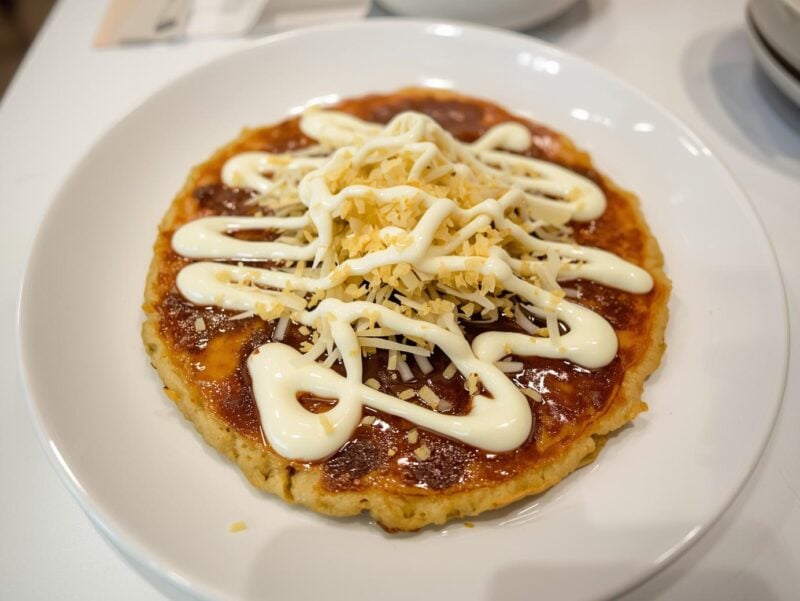A Japanese okonomiyaki topped with bonito flakes, mayo, and okonomiyaki sauce - one of the 15 Must-Try Asian Dishes