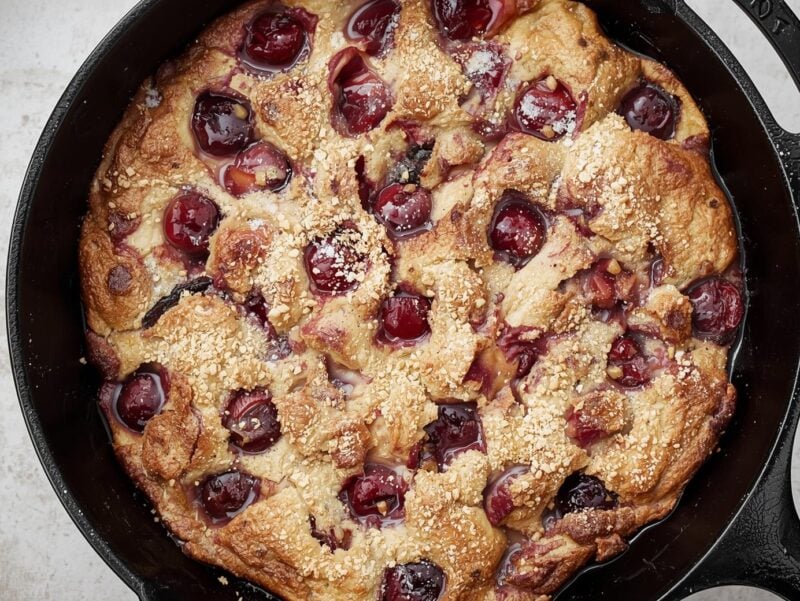Cherry clafoutis in a cast iron skillet with powdered sugar on top
