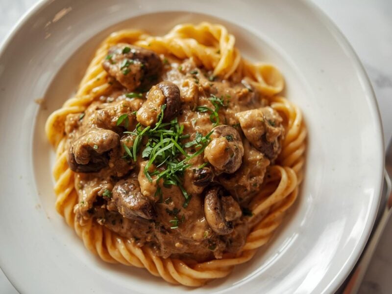 Creamy mushroom stroganoff served over pasta with fresh herbs